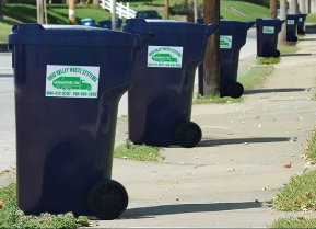 A row of garbage cans on the side of a street.